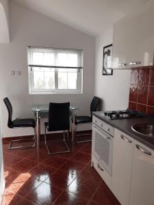eine Küche mit einem Tisch, Stühlen und einem Waschbecken in der Unterkunft Apartment Pag 16100c in Pag
