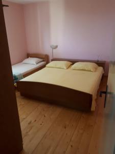 two beds in a room with wooden floors at Apartments by the sea Prigradica, Korcula - 16125 in Blato
