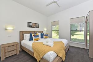 een slaapkamer met een groot bed met gele en blauwe kussens bij Ironbark Hill Villa 3 Saperavi in Pokolbin