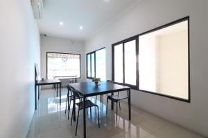 uma sala de jantar com mesas e cadeiras pretas e janelas em Uptown Residence Syariah Pondok Pinang em Jacarta