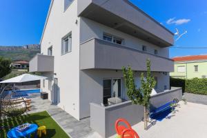 a white house with a swimming pool at Family friendly apartments with a swimming pool Kastel Kambelovac, Kastela - 16162 in Kaštela