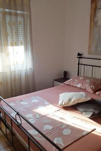 a bedroom with a bed with pink sheets and a window at Apartments by the sea Ploce, Neretva Delta - Usce Neretve - 16195 in Ploče