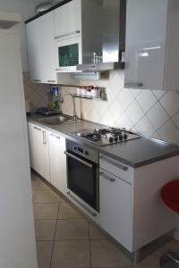 a kitchen with white cabinets and a stove top oven at Apartments by the sea Ploce, Neretva Delta - Usce Neretve - 16195 in Ploče