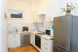 a kitchen with white cabinets and a stainless steel refrigerator at Apartments by the sea Trogir - 16210 in Trogir