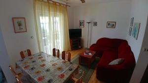 ein Wohnzimmer mit einem roten Sofa und einem Tisch in der Unterkunft Apartments by the sea Brgulje, Molat - 16217 in Molat