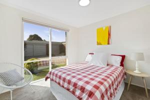 a white bedroom with a bed and a window at Bay Bright in Point Lonsdale