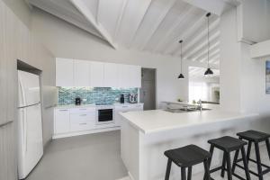 una cocina con armarios blancos y taburetes negros en Ocean Paradise, en Bonny Hills