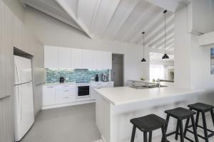 a kitchen with white cabinets and black stools at Ocean Paradise in Bonny Hills