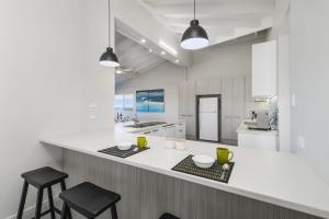 Una cocina con una encimera blanca y dos taburetes. en Ocean Paradise, en Bonny Hills