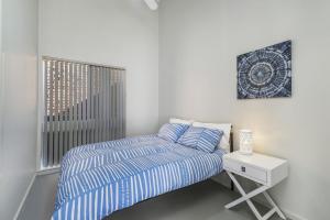 a bedroom with a bed and a nightstand and a window at Ocean Paradise in Bonny Hills