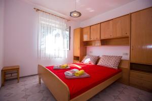 ein Schlafzimmer mit einem Bett mit roter Bettwäsche und Bananen darauf in der Unterkunft Apartments with a parking space Barbat, Rab - 16245 in Rab