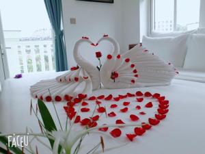 two white swans making a heart on a bed at INDOTEL HALONG HOTEL in Ha Long