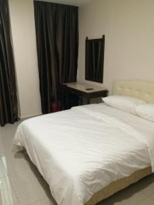 een slaapkamer met een wit bed en een bureau bij Sam Hotel in Sitiawan