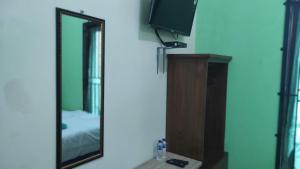espejo en una habitación con TV y tocador en RedDoorz near RSUD Kebumen 2, en Wanasari 8 fotos más