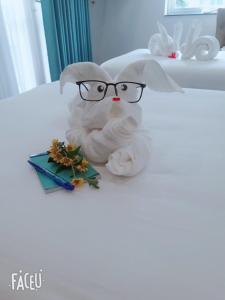 a stuffed animal with glasses sitting on a bed at INDOTEL HALONG HOTEL in Ha Long