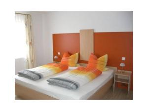 1 Schlafzimmer mit 2 Betten mit orangefarbenen und gelben Kissen in der Unterkunft Kempfenhof in Oberharmersbach