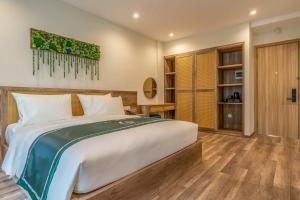 a bedroom with a large white bed and wooden floors at Bliss Hotel Phu Quoc in Phu Quoc