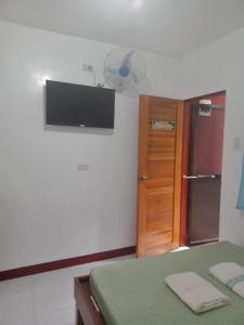 a room with a refrigerator and a television on the wall at Felipa Beach and Guesthouse - Newly Renovated Airconditioned Guest Rooms in Dumaguete