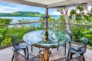 a glass table and chairs on a balcony with a view at Habitat on Hamilton Island by HIHA in Hamilton Island