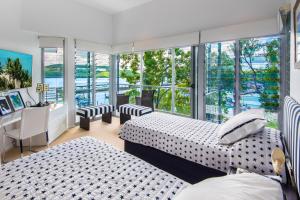 a bedroom with two beds and a desk and windows at Habitat on Hamilton Island by HIHA in Hamilton Island
