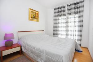 a bedroom with a bed and a table with a lamp at Apartments by the sea Arbanija, Ciovo - 15595 in Trogir