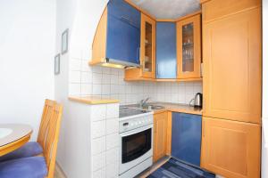 a small kitchen with blue cabinets and a sink at Apartments by the sea Arbanija, Ciovo - 15595 in Trogir