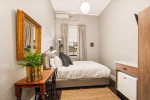 a bedroom with a bed and a table and a mirror at The Commercial Quarters in Millthorpe