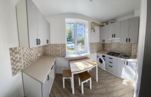 a kitchen with white cabinets and a table and a window at Complex Zolota Pidkova in Zolochiv