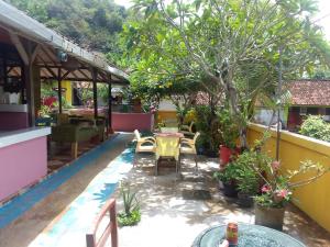 un patio con mesa, sillas y un árbol en Alola inn, en Padangbai
