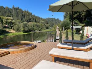 eine Holzterrasse mit 2 Liegestühlen und einem Sonnenschirm in der Unterkunft Boho Manor in Monte Rio