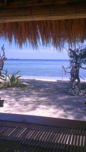 - une vue sur l'océan depuis une plage dotée d'un toit de paille dans l'établissement Family bungalow, à Gili Meno