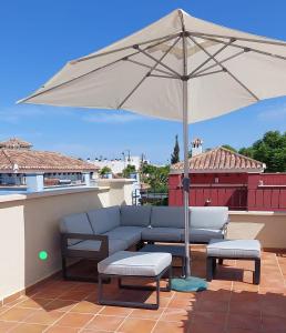 a couch and an umbrella on a patio at 2-bedroom Villa with pool in Torre-Pacheco