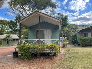 a green house with a porch in a yard at Big4 Aussie Outback Oasis Holiday Park in Charters Towers