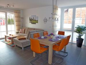 ein Wohnzimmer mit einem Holztisch und orangefarbenen Stühlen in der Unterkunft Heubude in Greetsiel