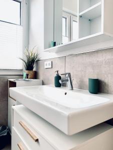 ein Badezimmer mit einem weißen Waschbecken und einem Spiegel in der Unterkunft Modernes Apartment am See mit Terrasse in Großräschen