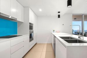 a white kitchen with white cabinets and a sink at Aquaview Unit 304 Kings Beach in Caloundra