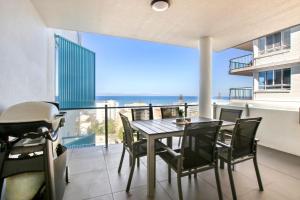 a table and chairs on a balcony with a view of the ocean at Aquaview Unit 304 Kings Beach in Caloundra