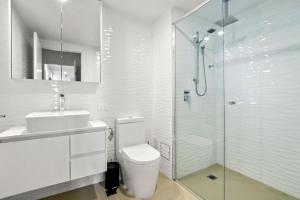 a white bathroom with a toilet and a shower at Aquaview Unit 304 Kings Beach in Caloundra +4 photos