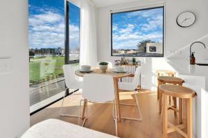a dining room with a table and chairs and a large window at Top Floor Luxury City Central w Sunny Balcony in Christchurch