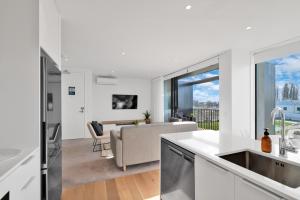 a kitchen and living room with a couch and a table at Top Floor Luxury City Central w Sunny Balcony in Christchurch