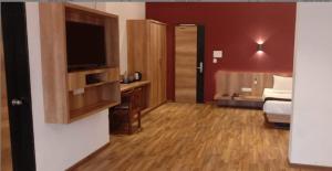 TGN SUITES - HOTEL في رايبور: غرفة فندقية بسرير وتلفزيون بشاشة مسطحة