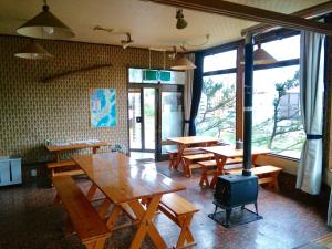 un restaurante con mesas de madera, bancos y ventanas en Matsuo House - Max 4 person Room Aki en Zao Onsen