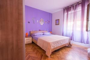 een slaapkamer met paarse muren, een bed en een raam bij Apartments with a parking space Kastel Sucurac, Kastela - 16209 in Kaštela