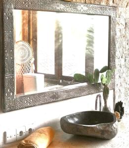 a bathroom sink with a mirror and a rock sink sidx sidx sidx at Sannyas Boutique Hotel in Uluwatu