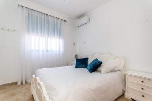 a white bedroom with a white bed with blue pillows at Reel Paradise Villa, Cyprus in Larnaca