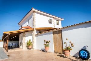 a white house with potted plants in front of it at Reel Paradise Villa, Cyprus in Larnaca