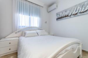a white bedroom with a white bed and a window at Reel Paradise Villa, Cyprus in Larnaca