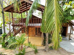 mały drewniany budynek z gankiem i palmą w obiekcie Another World w mieście Arugam Bay