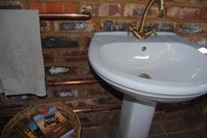 a white sink in a bathroom with a brick wall at Grotto to Gravel in Magaliesburg