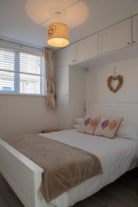 a white bedroom with a large bed and a heart mirror at Hegarty's cottage at Trevarrian Lodge in Mawgan Porth